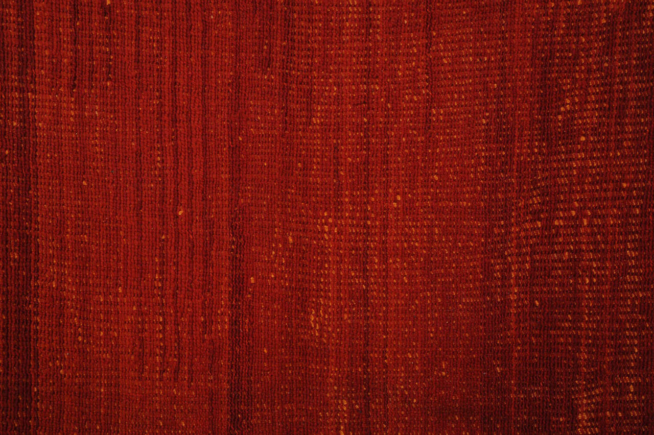 A unique flat-weave with a very robust texture obtained by brocading a warp-faced fabric composed of very thick woolen light orange wefts. It is inspired by the reed carpets of the Tuareg people of Mauritania. The fact that the Sumak brocading is